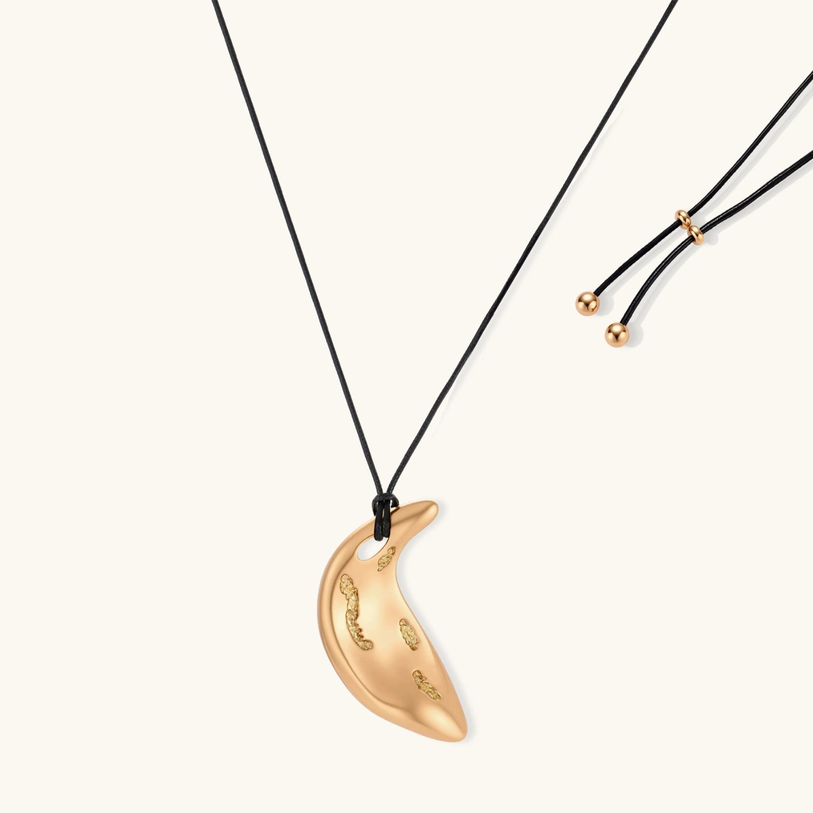 Adjustable crescent moon pendant necklace in gold and silver eco-zinc alloy with decorative engravings on black cord