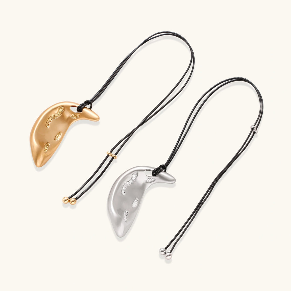 Adjustable crescent moon pendant necklace in gold and silver eco-zinc alloy with decorative engravings on black cord